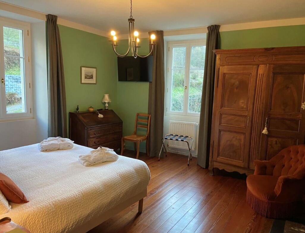 Ein Schlafzimmer mit einem Bett, einem Holzschrank, einem Schreibtisch mit Stuhl und einer Heizung.