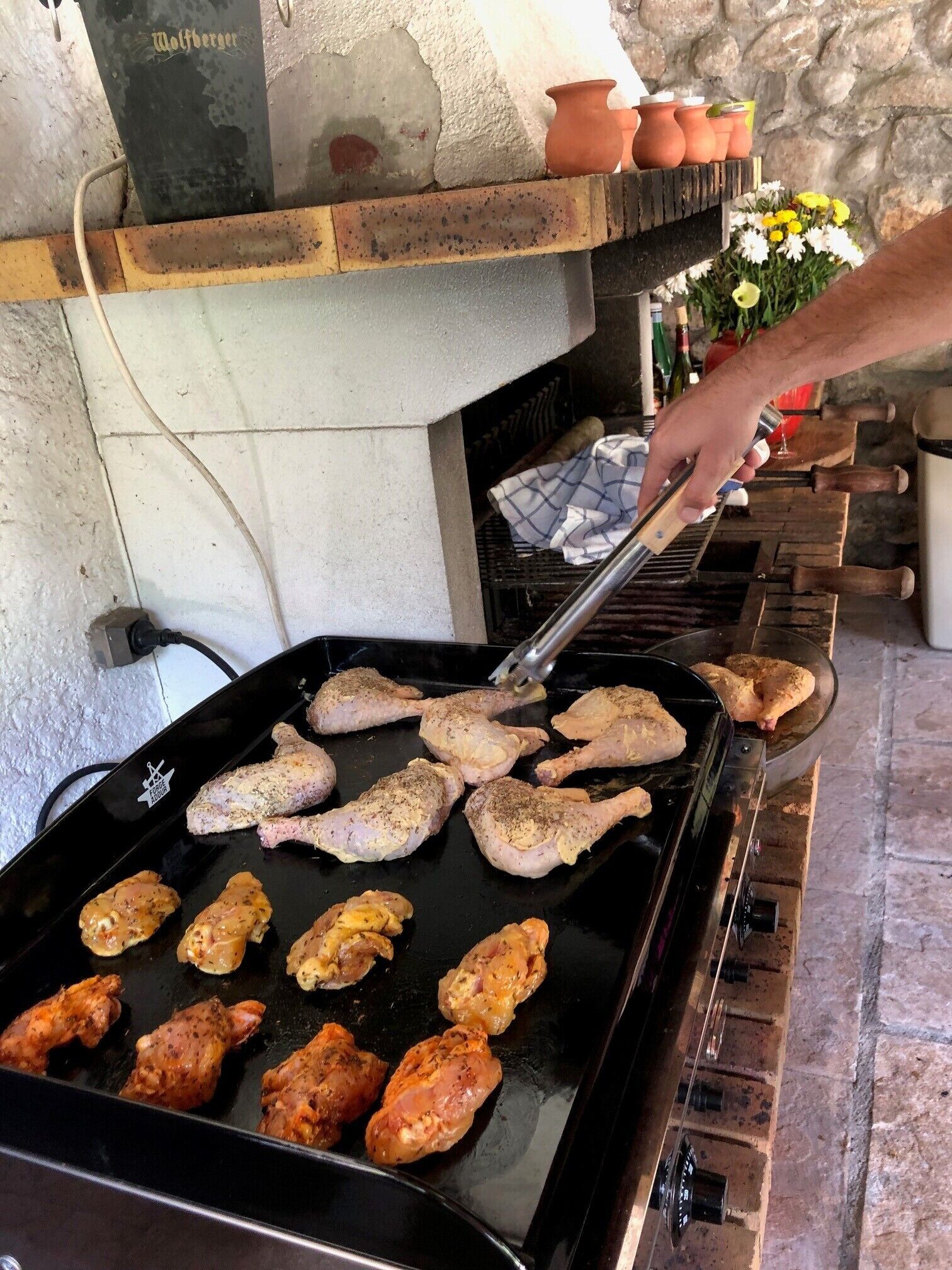 A person grilling chicken on an outdoor grill.