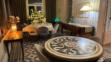Un coin repas avec une table ronde, des chaises, un sapin de Noël et un mur orné d’un tableau encadré.