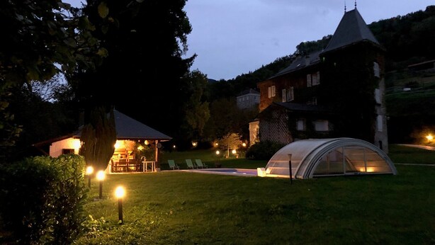 A well-lit outdoor area with a gazebo, a greenhouse, and a large house with a steep roof. - Le Clos Du Tulipier  (La Chapelle-du-Bard)