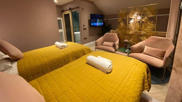A hotel room with two beds, a TV, a small table, and a chair. - Ailim House Serviced Cottage (St. Andrews)