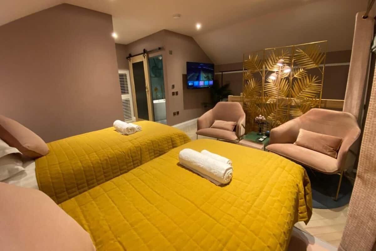 A hotel room with two beds, a TV, a small table, and a chair.