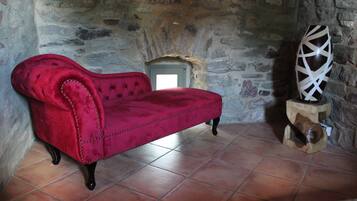 A red velvet sofa in a stone-walled room with a tiled floor.