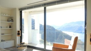 Un salon moderne avec une grande fenêtre, un canapé, un fauteuil et une petite table.