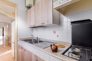 Een koelkast, een oven, een kookplaat, kookgerei, borden en bestek