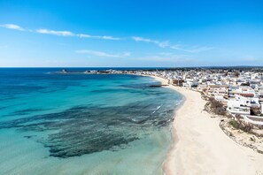 A coastal town with a beach, buildings, and a clear blue sky.