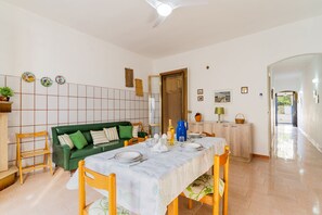 A dining area with a table set for four, a green sofa, and a tiled floor.