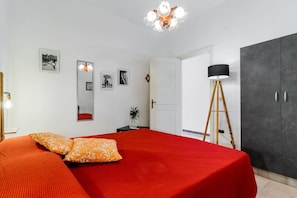 A bedroom with a large bed, a wardrobe, a mirror, and a lamp.