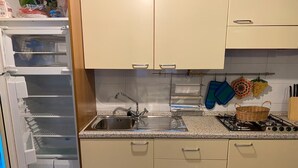 Une cuisine équipée d’un réfrigérateur, d’un évier, d’une cuisinière et de placards.