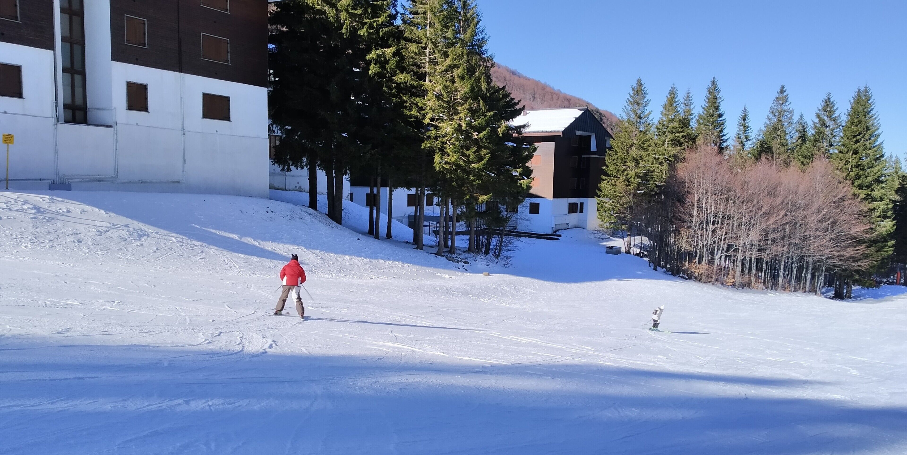 A ski slope with a building in the background.