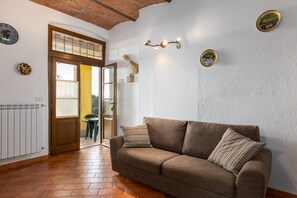 A room with a brown sofa, a wooden door, a radiator, and a wall clock.