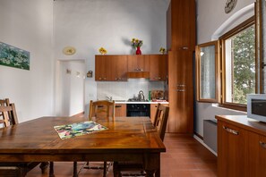 A kitchen with wooden cabinets, a dining table, chairs, a small refrigerator, and a window with a view.