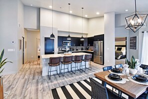 A modern kitchen with a central island, bar stools, and pendant lighting.