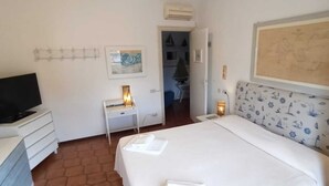 A hotel room with a bed, a desk with a lamp, a television, and a map on the wall. - Simone Mare (CIN: IT046033C2FHIIU2HV) (Torre del Lago Puccini)