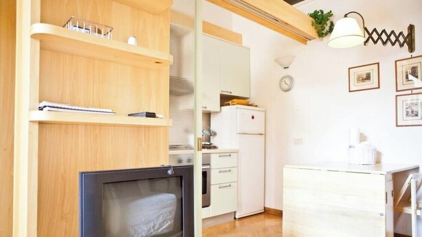 Eine kleine Küche mit Holzböden, einem eingebauten Backofen und einem weißen Kühlschrank.