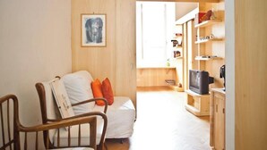 A cozy living room with a sofa and chairs, a television, and a bookshelf. - Loft in The heart of Ancient Rome (Roma)