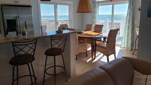 A kitchen with a large window, a dining area with wicker chairs, and a sofa. - Beachfront home with beautiful view of beach and ocean. (Port St. Joe)