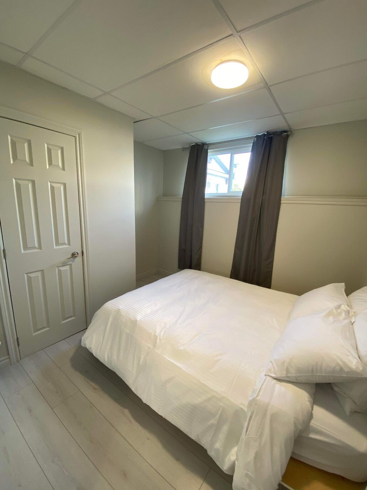 Un dormitorio con cama, una puerta y una ventana con cortinas.