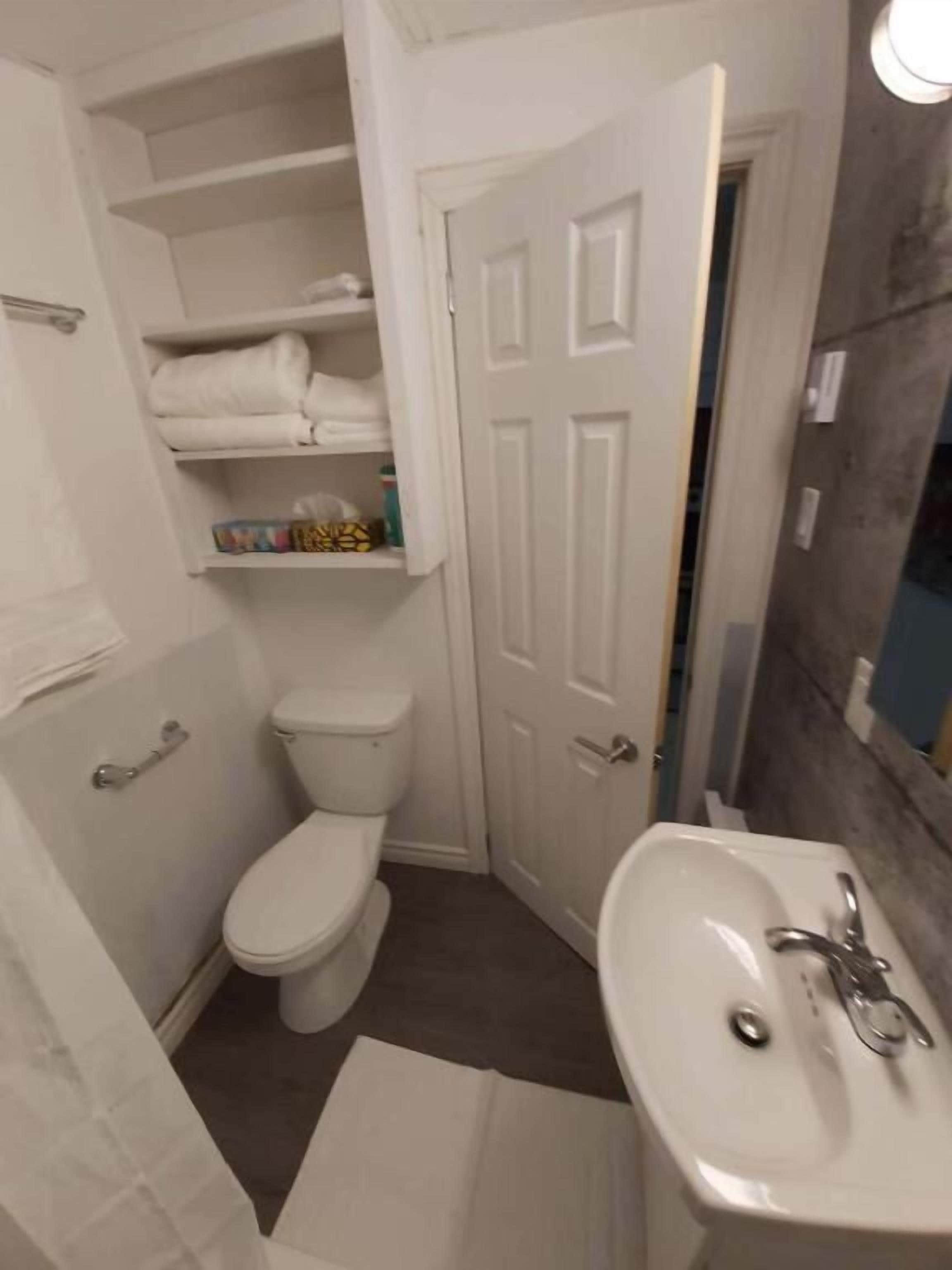 A compact bathroom with a toilet, a sink, and a shower area.