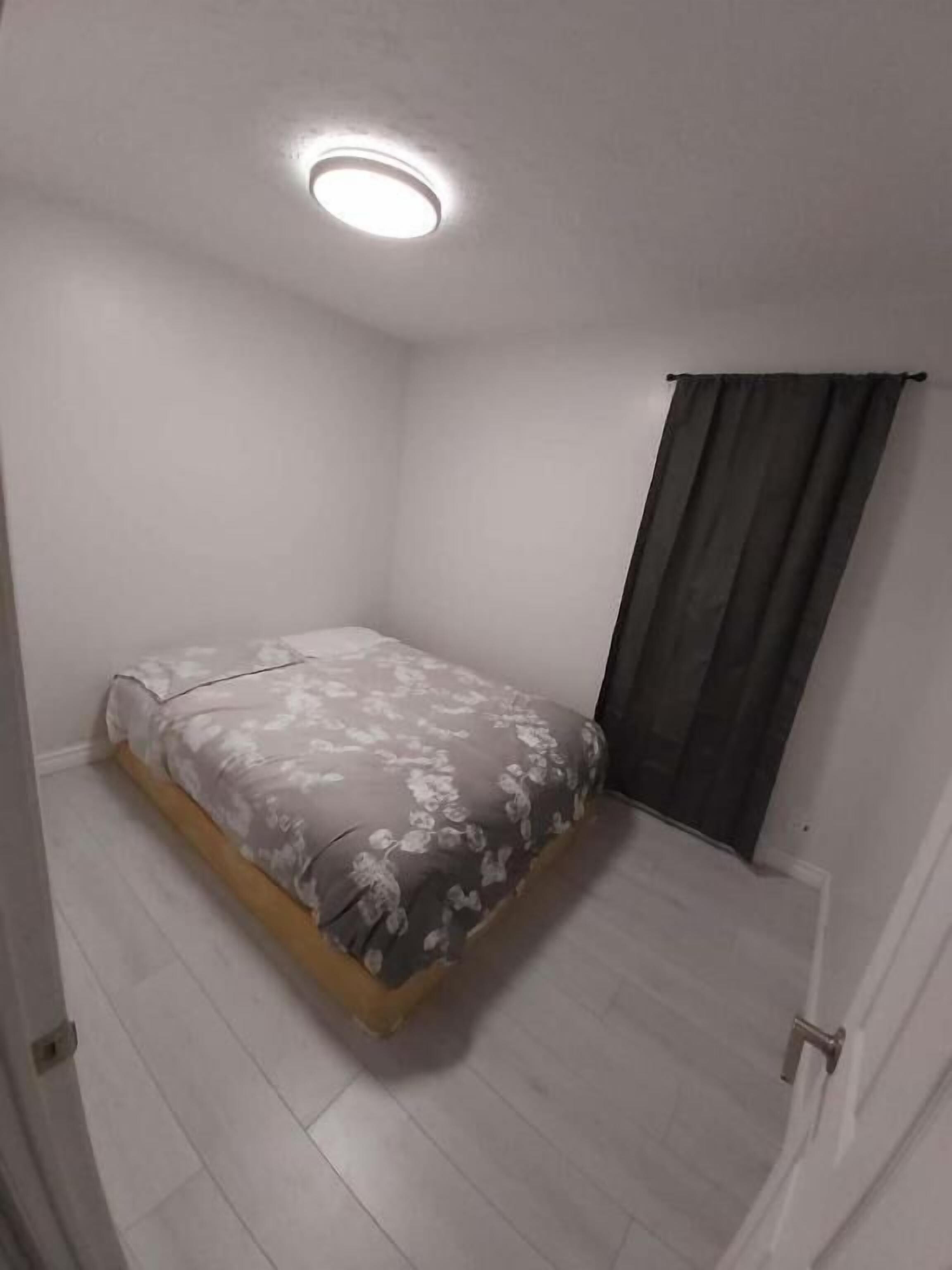 A bedroom with a bed, a door, and a window with curtains.