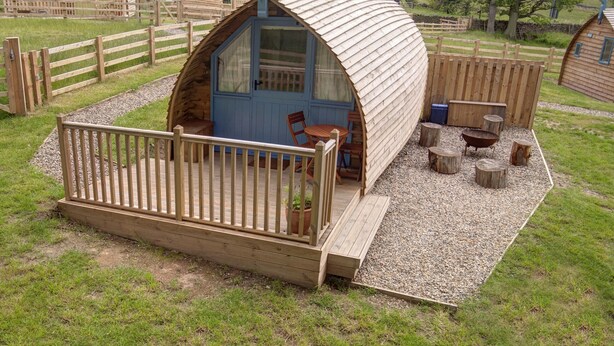 A small, dome-shaped wooden cabin with a wooden deck and seating area.