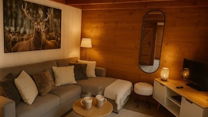 Ein gemütliches Zimmer mit einer Couch, einem Couchtisch, einem Fernseher und einem Spiegel.