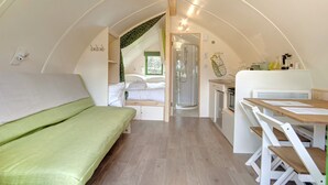 Une pièce compacte et bien éclairée, comprenant un lit, une douche et un petit coin cuisine.