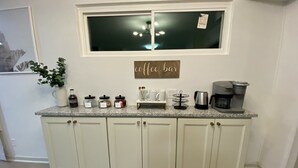 Une cuisine équipée d’un coin café comprenant des bocaux, des tasses, une machine à café et une bouilloire.