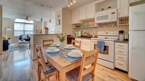 Una cucina moderna con mobili bianchi, un tavolo da pranzo in legno e un forno a incasso.