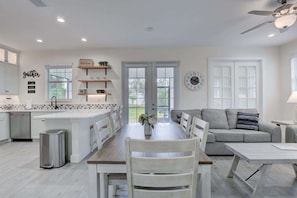 A modern kitchen with white cabinetry, a central island, and a dining area with a table and chairs.