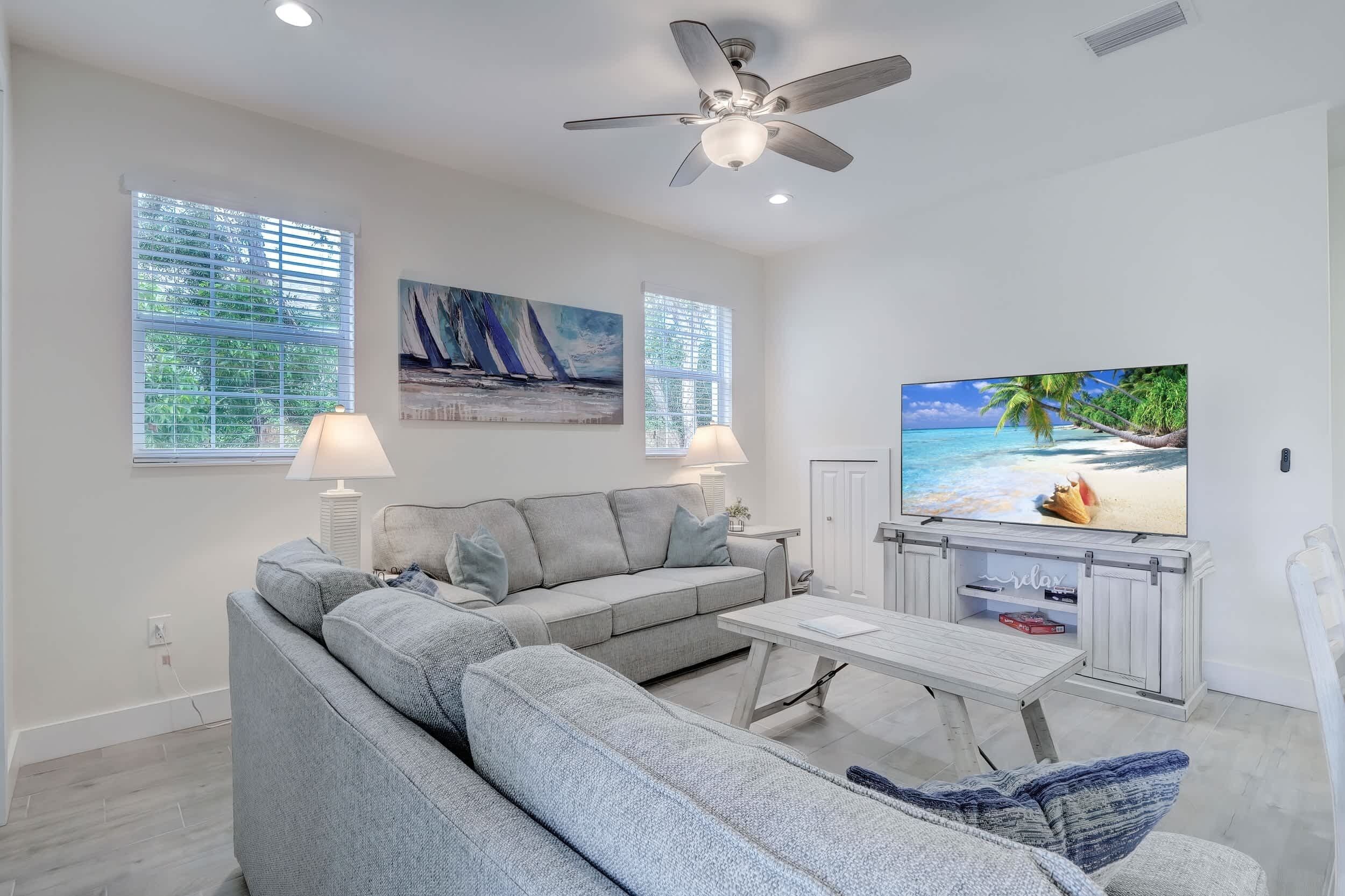 A modern living room with a grey sectional sofa, a flat-screen TV, and artwork on the walls.