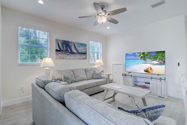 A modern living room with a grey sectional sofa, a flat-screen TV, and artwork on the walls.