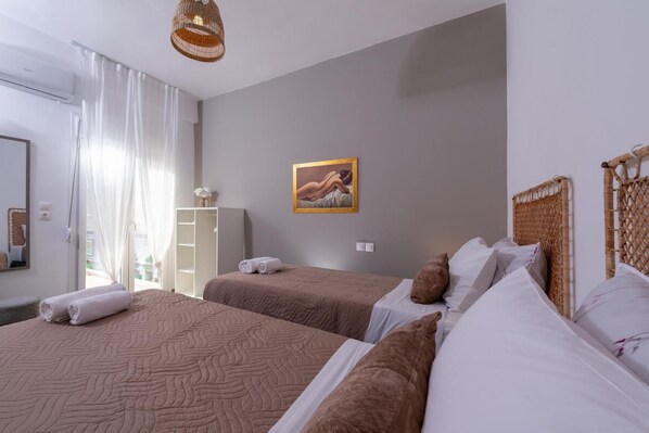 A hotel room with two beds, a large mirror, a painting on the wall, and a wardrobe.