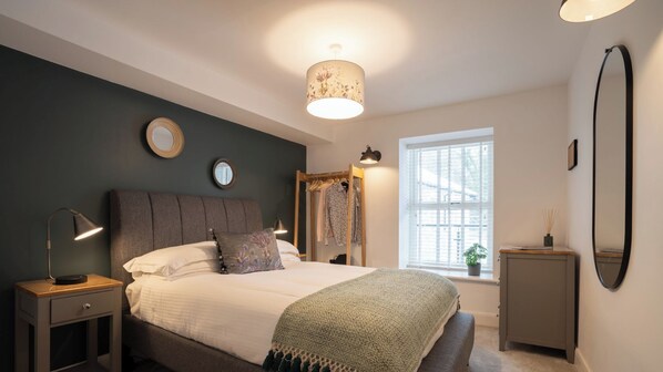 A bedroom with a bed, bedside tables, a window, and a mirror.