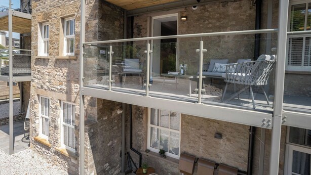 A stone building with a balcony, a wooden ceiling, and a window with a view.