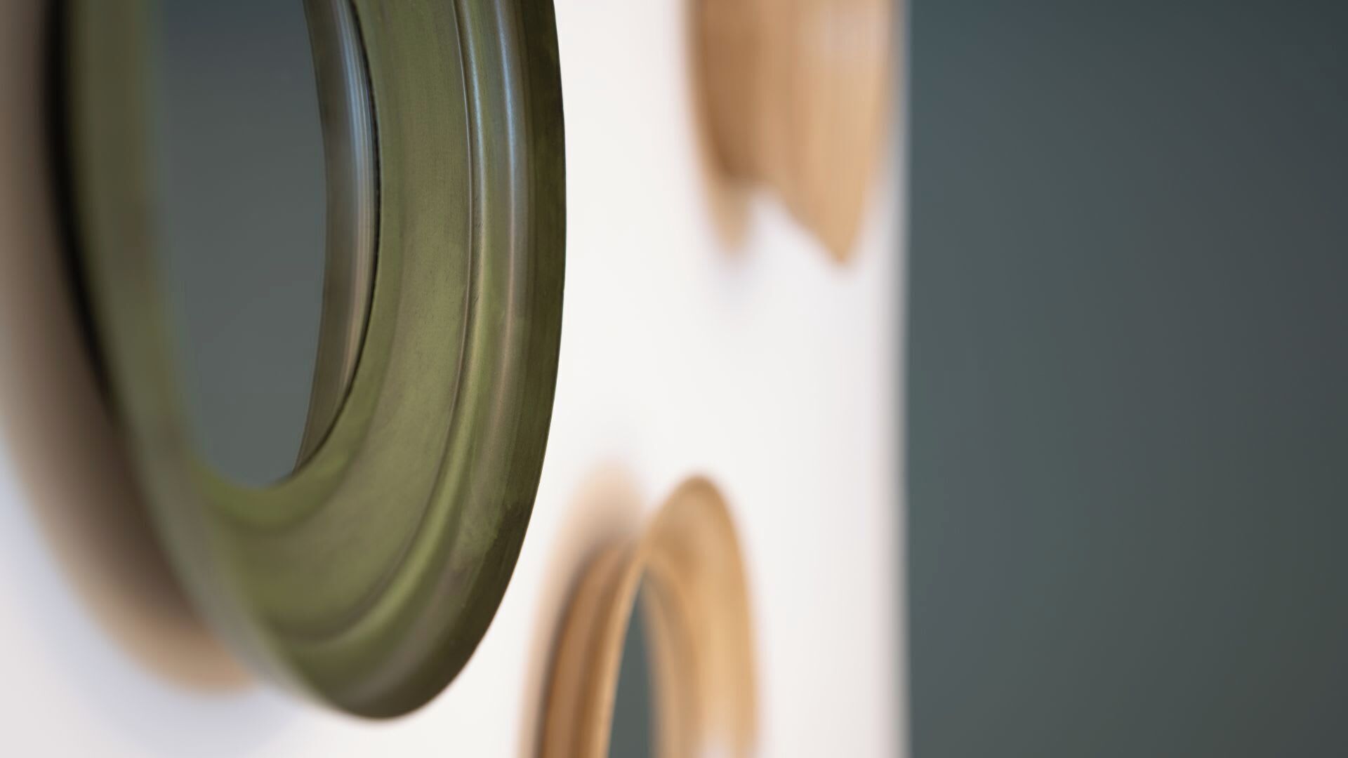 A close-up of a wall with a circular object, possibly a mirror, and a blurred rectangular object.