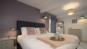 A bedroom with a bed, bedside tables, a mirror, and a tray with mugs.