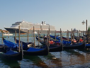 A cruise ship docked at a harbor with gondolas lined up in the foreground.