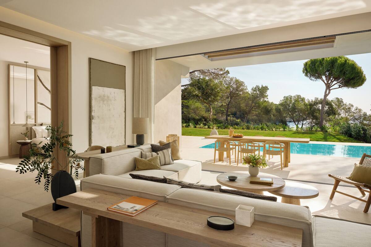A modern living room with a sofa, coffee table, and a view of a swimming pool.