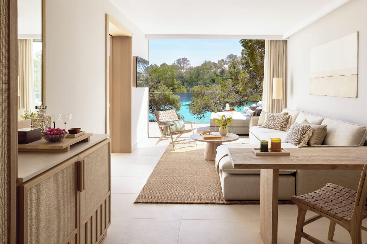 A modern living room with a view of a lake, a sofa, a coffee table, and a dining table.
