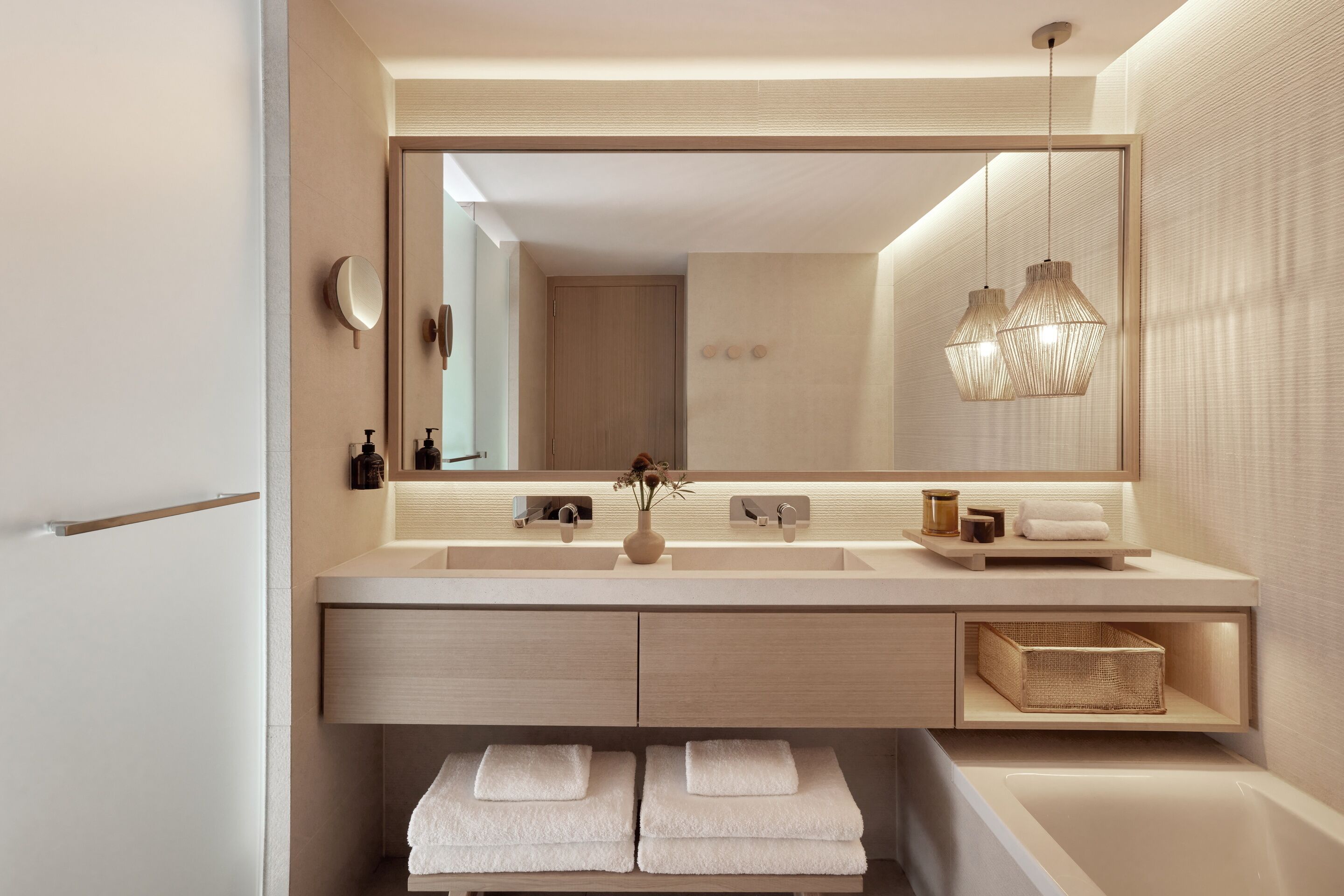 Un baño moderno con un espejo grande, un lavamanos, un perchero para toallas e iluminación colgante.