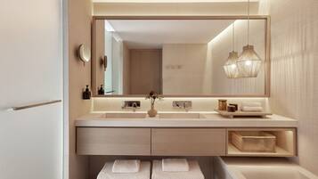 Un baño moderno con un espejo grande, un lavamanos, un perchero para toallas e iluminación colgante.