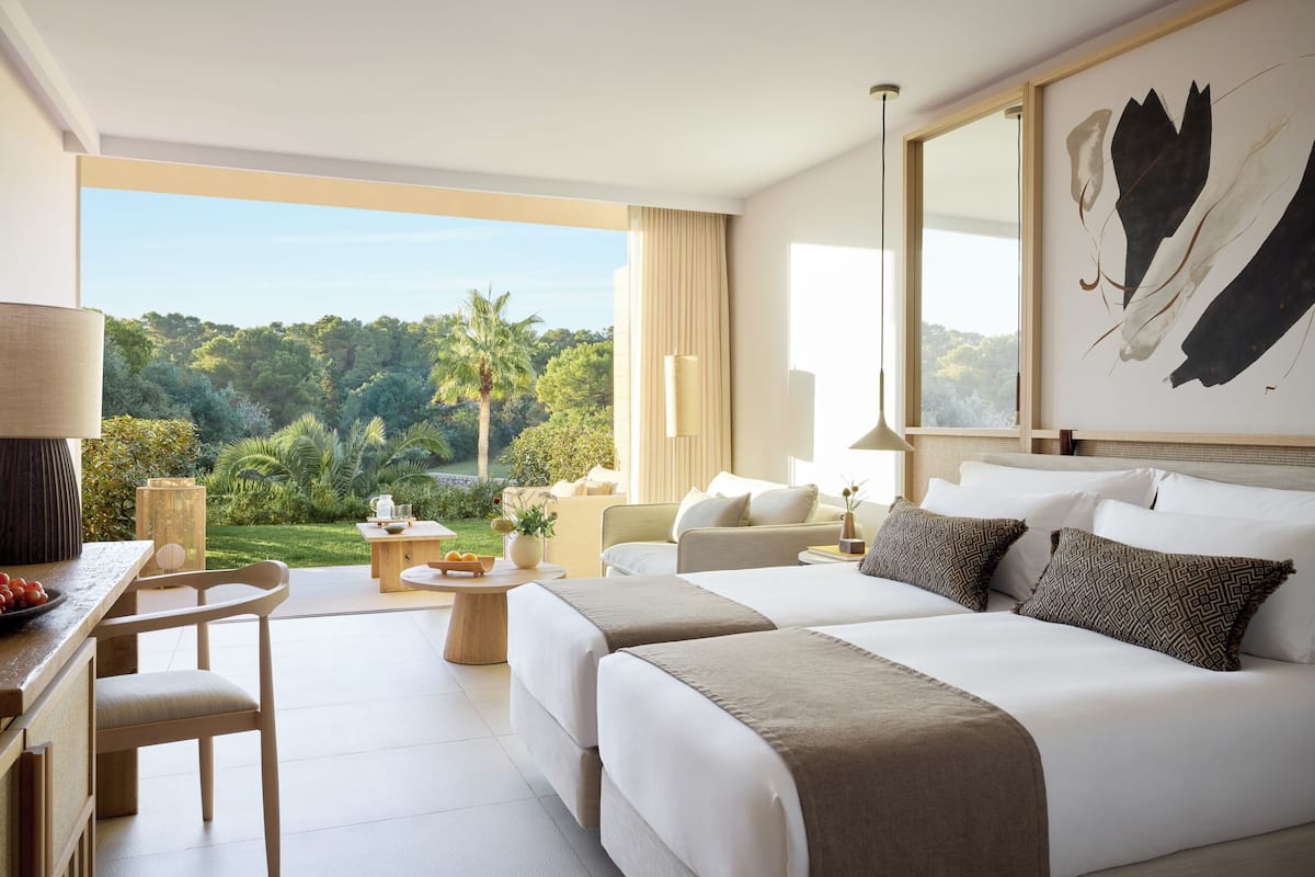 A hotel room with a large window, a bed, a desk, and a chair.