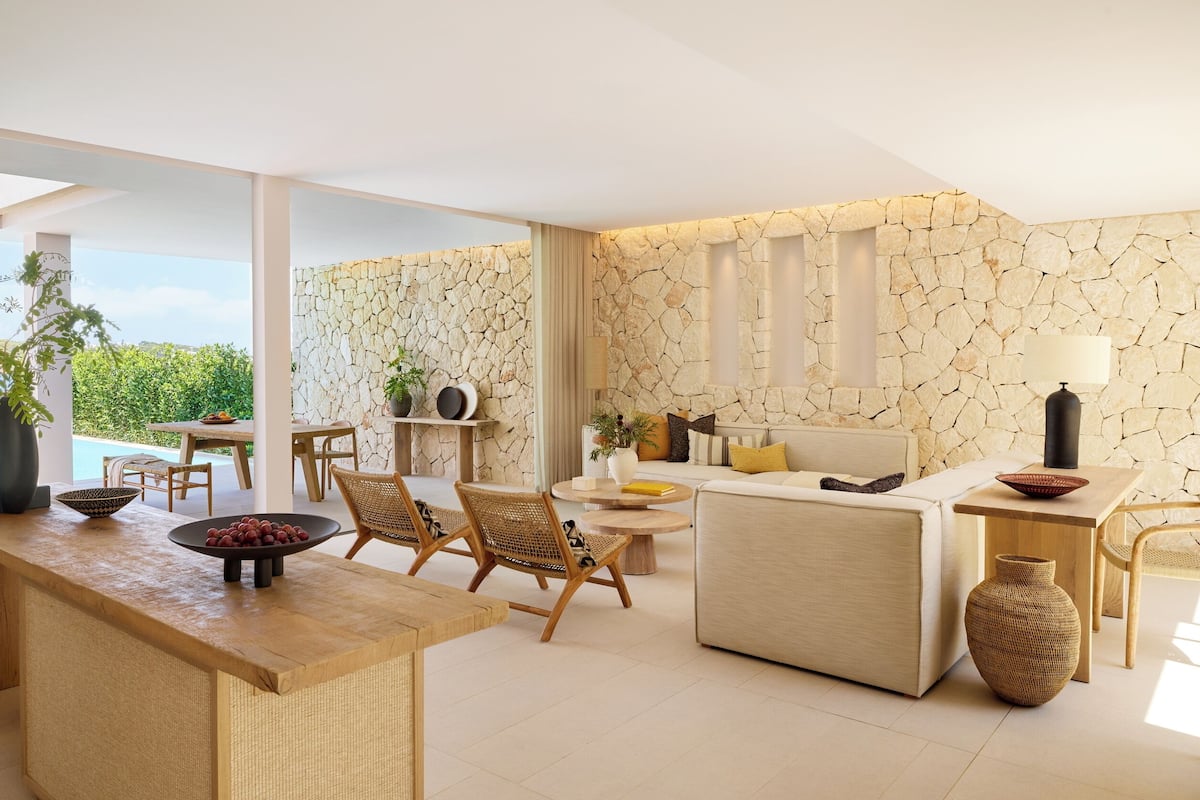 A modern living room with a stone wall, a sofa, a dining area with a table, and a view of the outdoors.