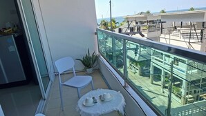 A balcony with a white chair, a small table with a white tablecloth, and a potted plant. - The Sunset Bangsaen Seaview (Chonburi)