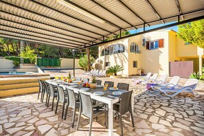 A covered outdoor dining area with a pool, lounge chairs, and a stone-tiled patio. - Villa Enzo Moraira - Eight Bedroom Villa, Sleeps 15 (Moraira)