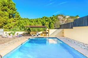 A swimming pool with lounge chairs and a covered seating area, surrounded by greenery and a hillside. - Villa Enzo Moraira - Eight Bedroom Villa, Sleeps 15 (Moraira)