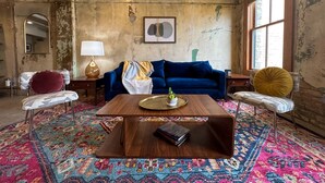 A living room with a blue sofa, a wooden coffee table, a patterned rug, and a large window. - Alamo Downtown San Antonio (San Antonio)