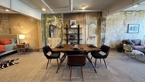 A dining area with a wooden table and four chairs, a sofa, and a small side table with a lamp. - Alamo Downtown San Antonio (San Antonio)