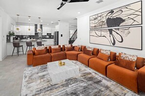 Uma sala de estar moderna com sofá modular, uma mesa de centro de mármore e um grande quadro abstrato na parede.